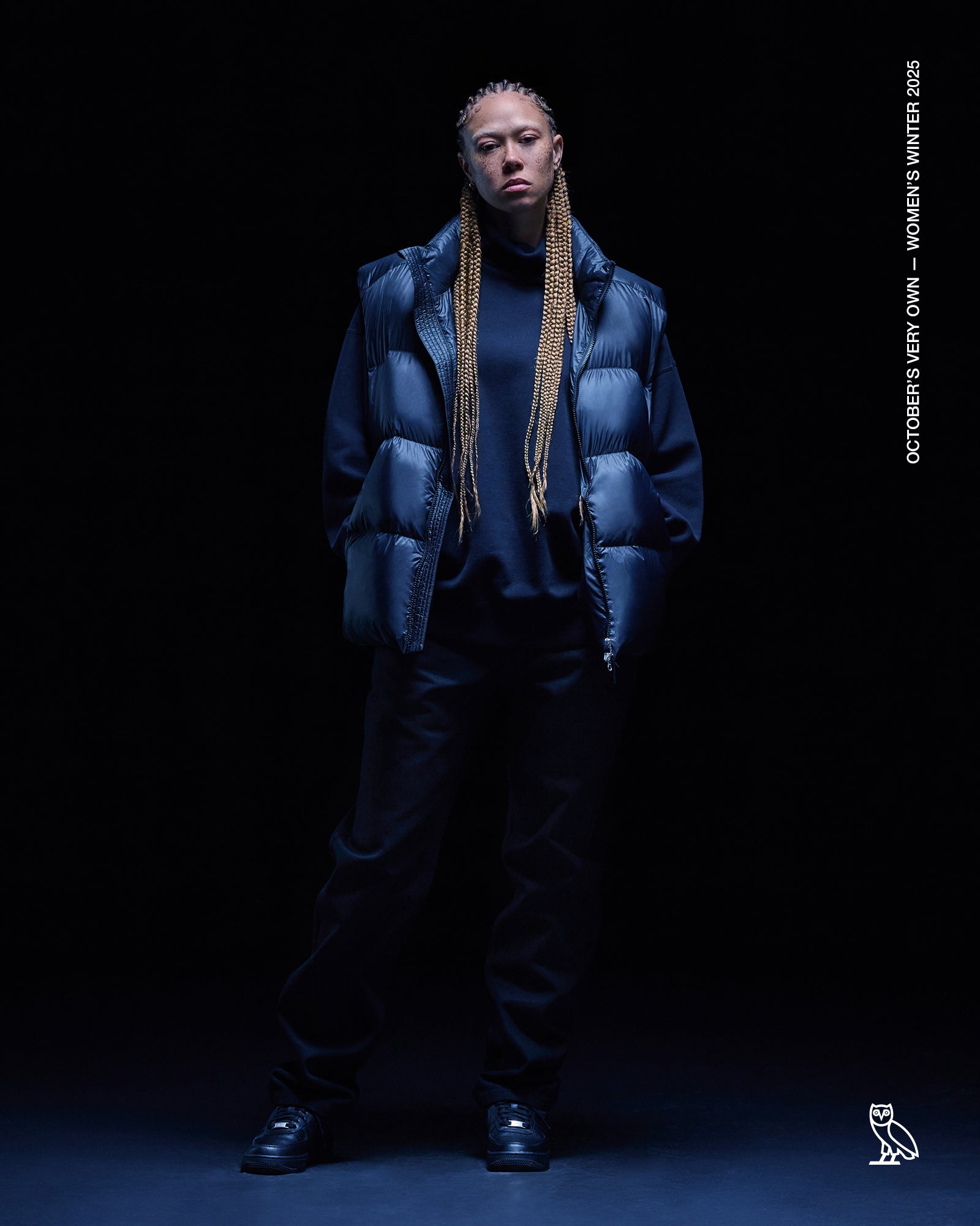 Person wearing a October's Very Own blue puffer jacket against a black background