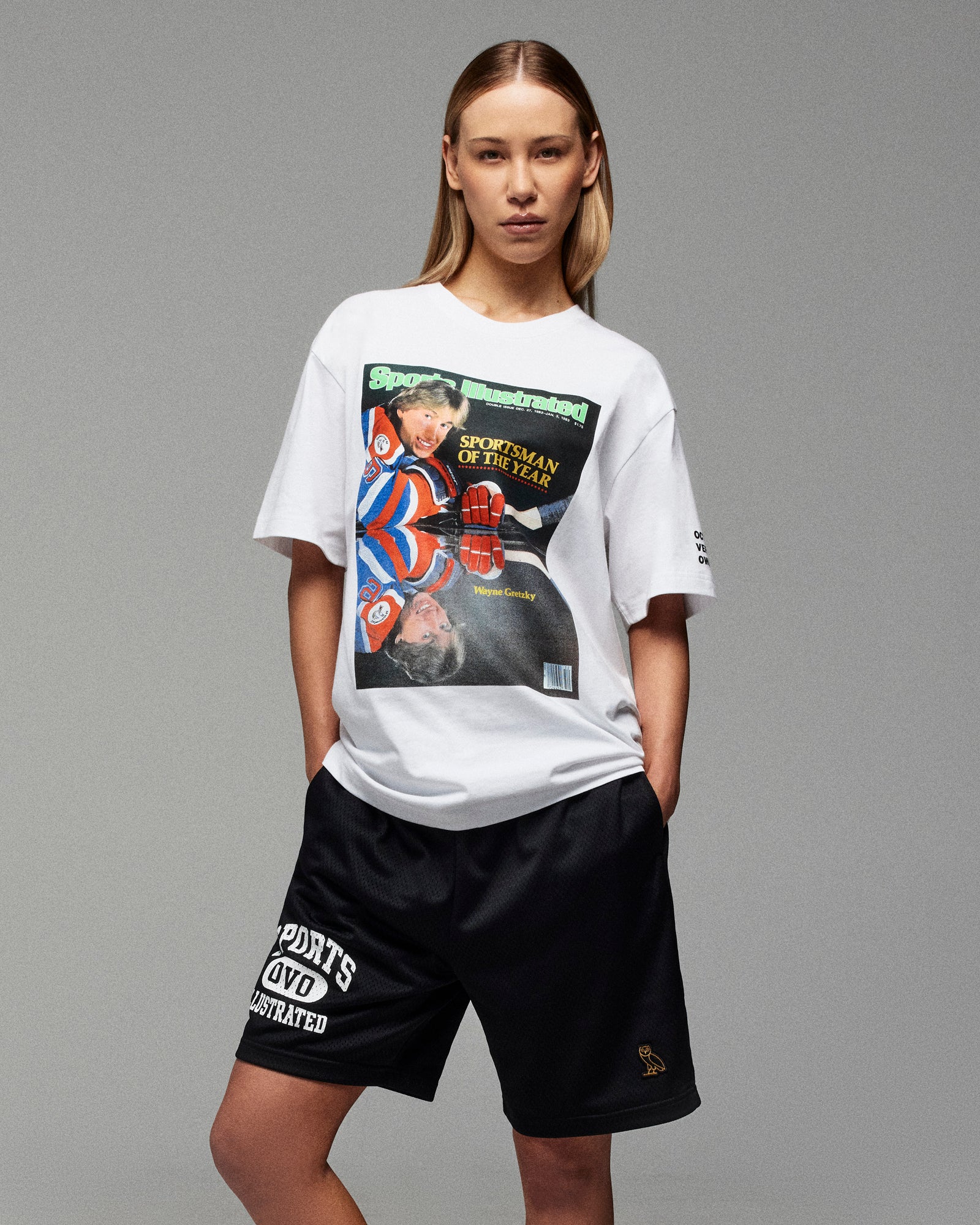Person wearing a black October's Very Own x Sports Illustrated t-shirt against a light background
