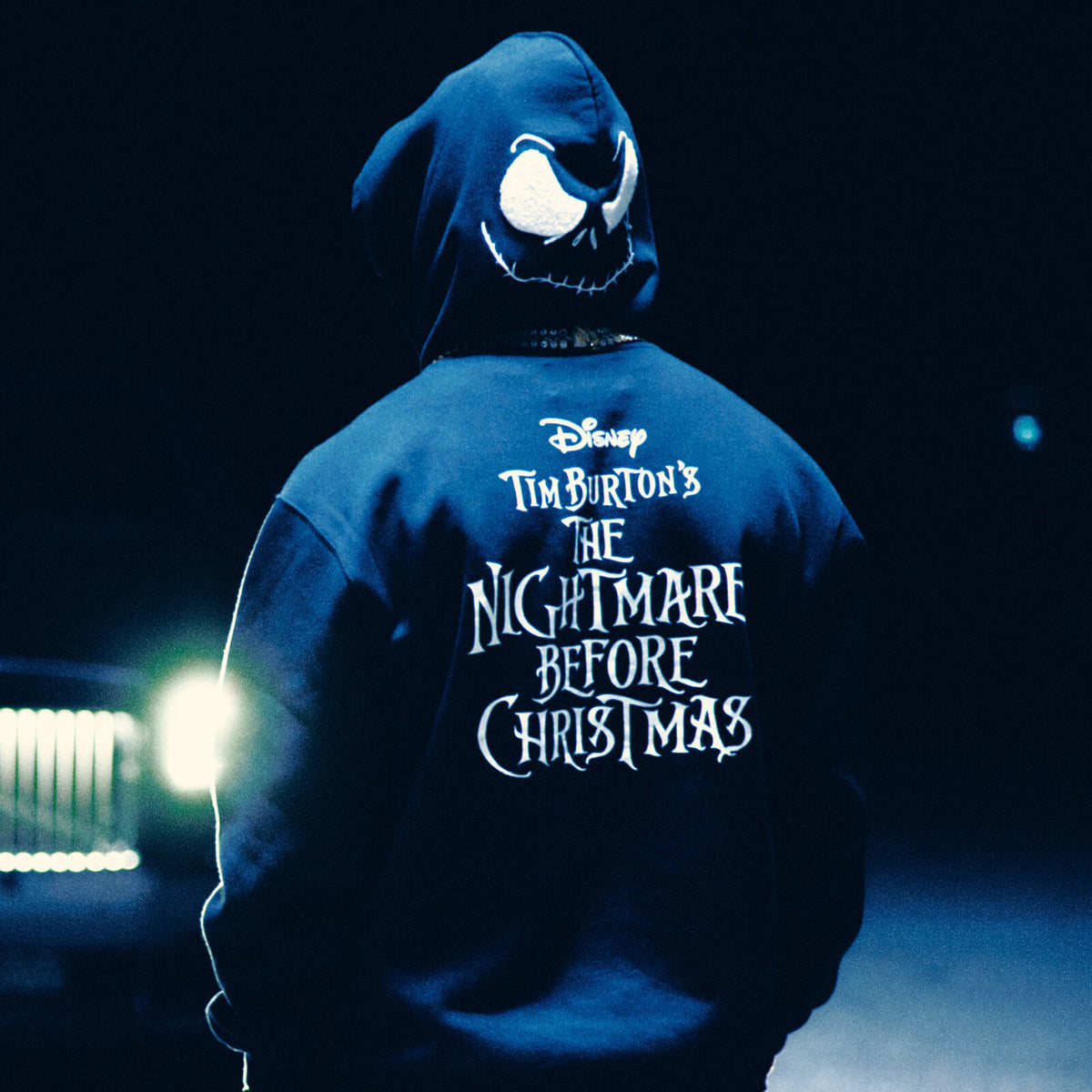 Person wearing a blue October's Very Own hoodie with 'The Nightmare Before Christmas' text on the back, dark background