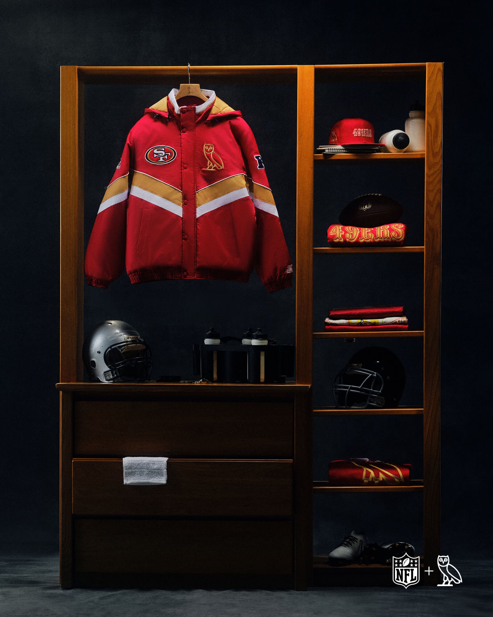 October's Very Own x NFL Red jacket with sports team logos on a wooden locker with shelves displaying various items against a dark background.