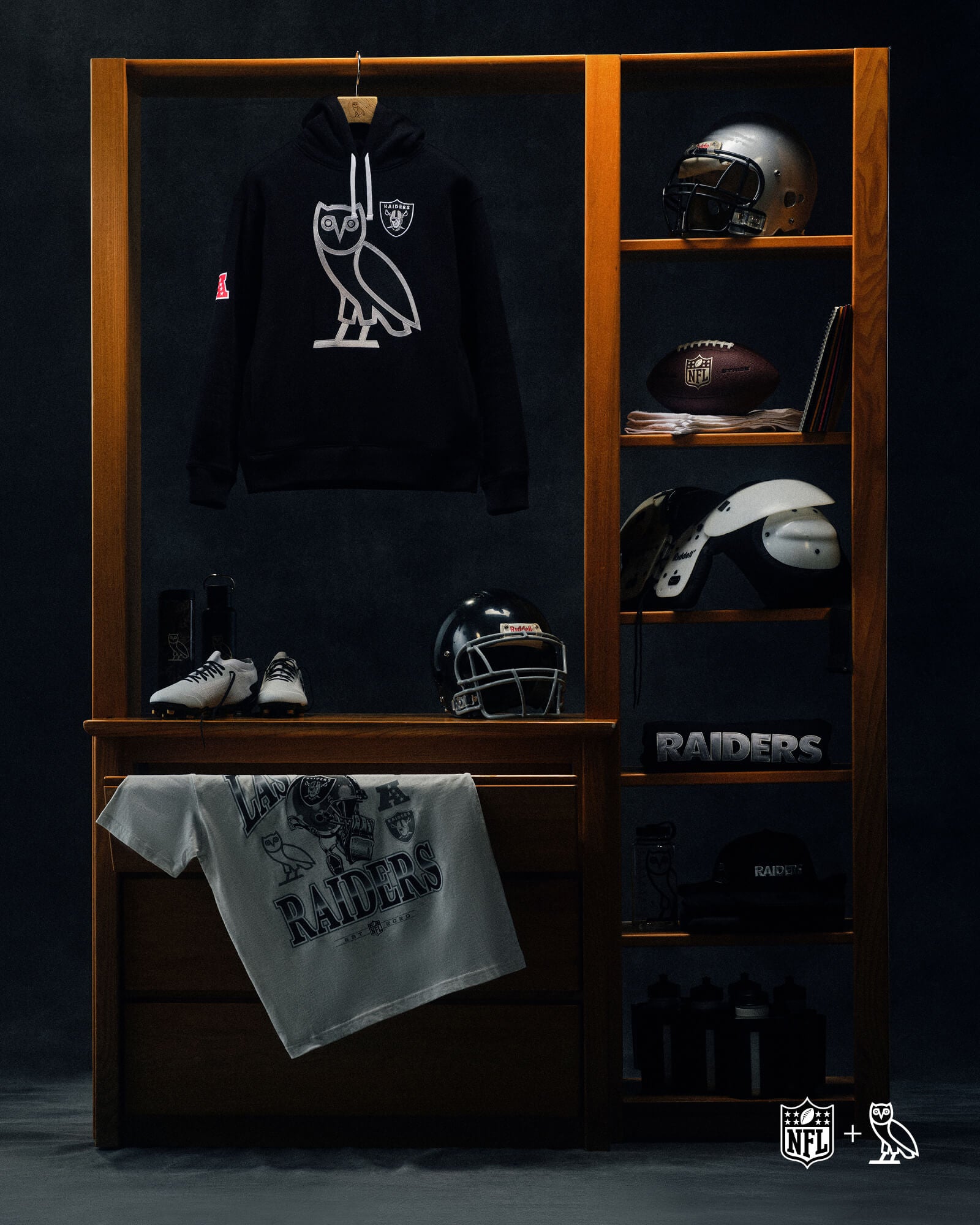 Display of October's Very Own Oakland Raiders merchandise including a hoodie, towel, and helmets on a wooden rack.