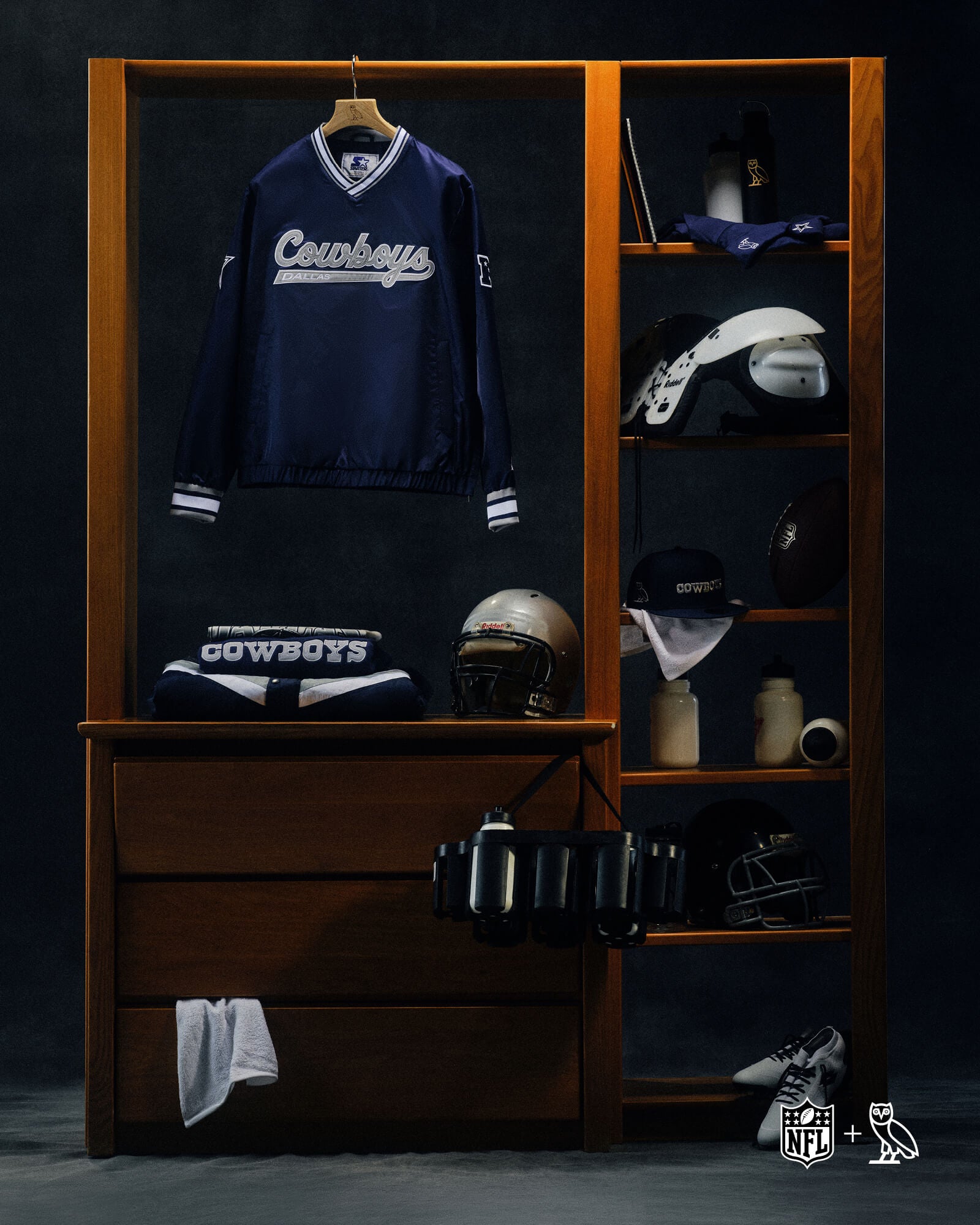 Wooden locker with sports gear, including a October's Very Own x NFL Cowboys jersey and helmets, on a dark background.