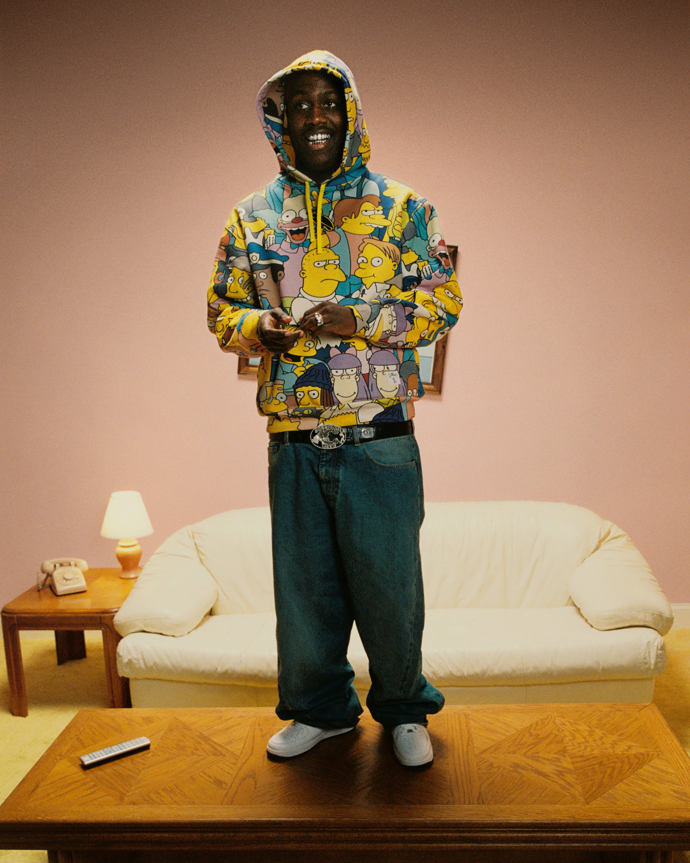 Lil Yachty wearing a October's Very Own colorful hooded sweatshirt in a living room setting