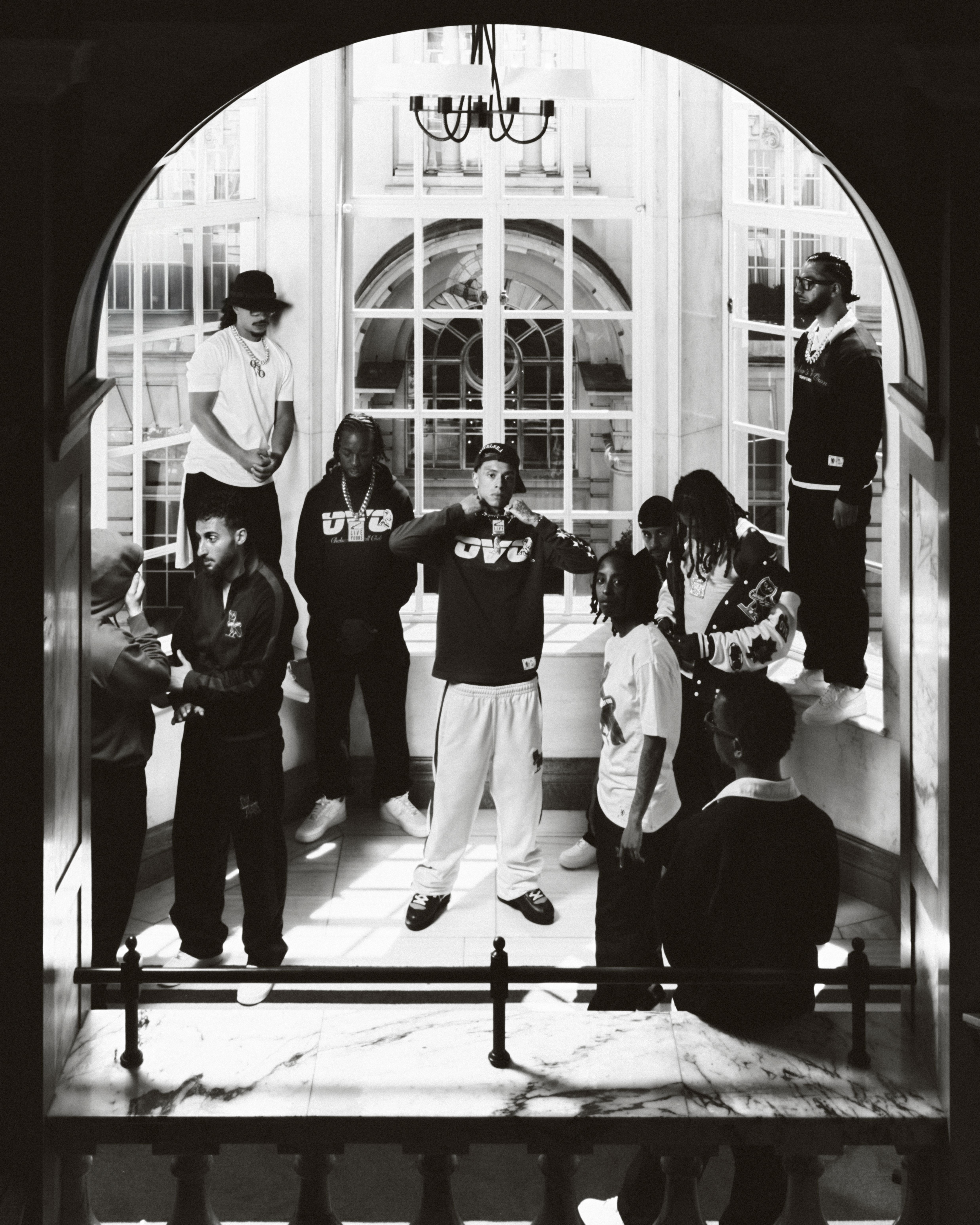 Group of people in a room with large windows and a chandelier wearing the October's Very Own x Chelsea FC Collection.