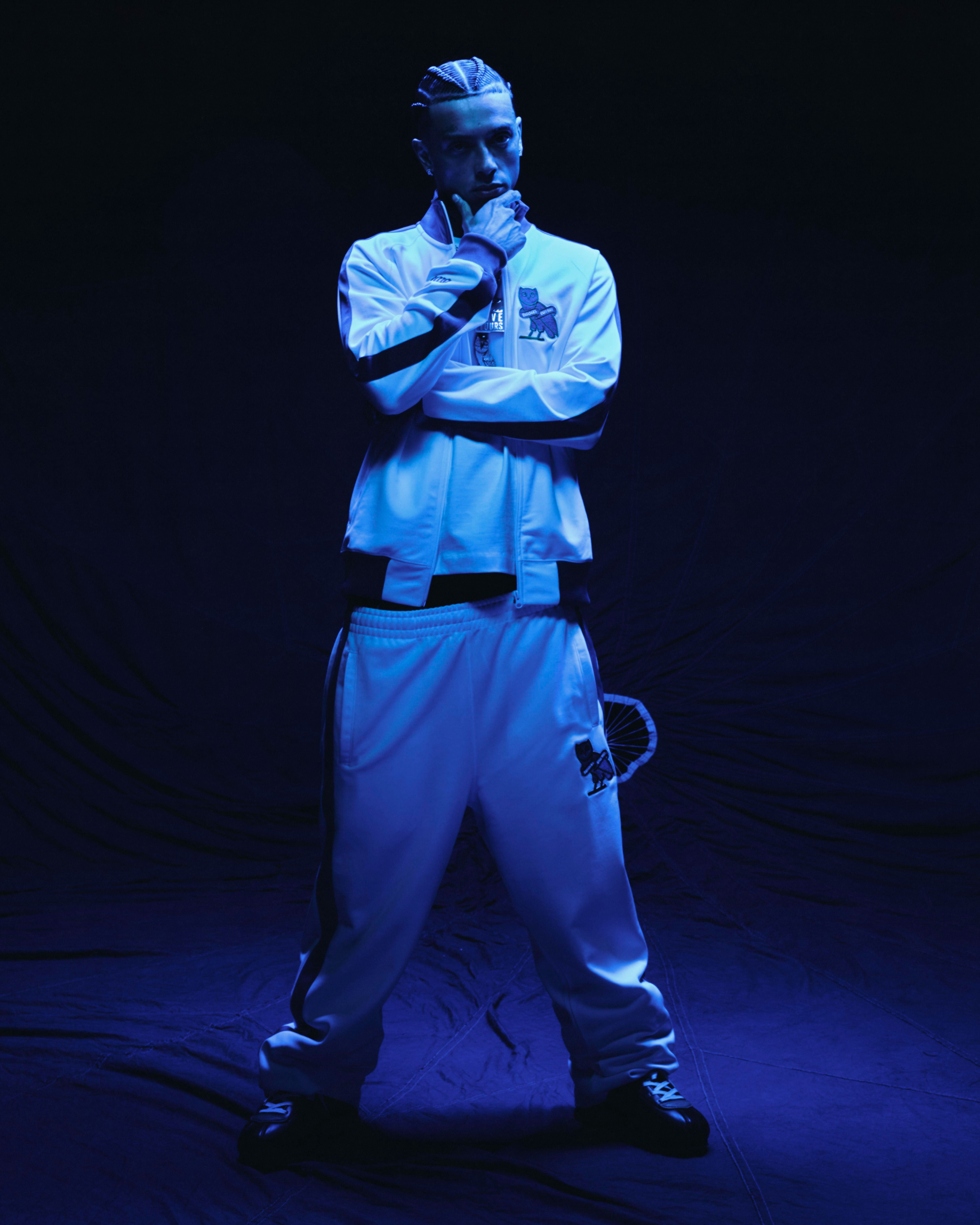 Central Cee in a white October's Very Own x Chelsea FC outfit posing against a dark background