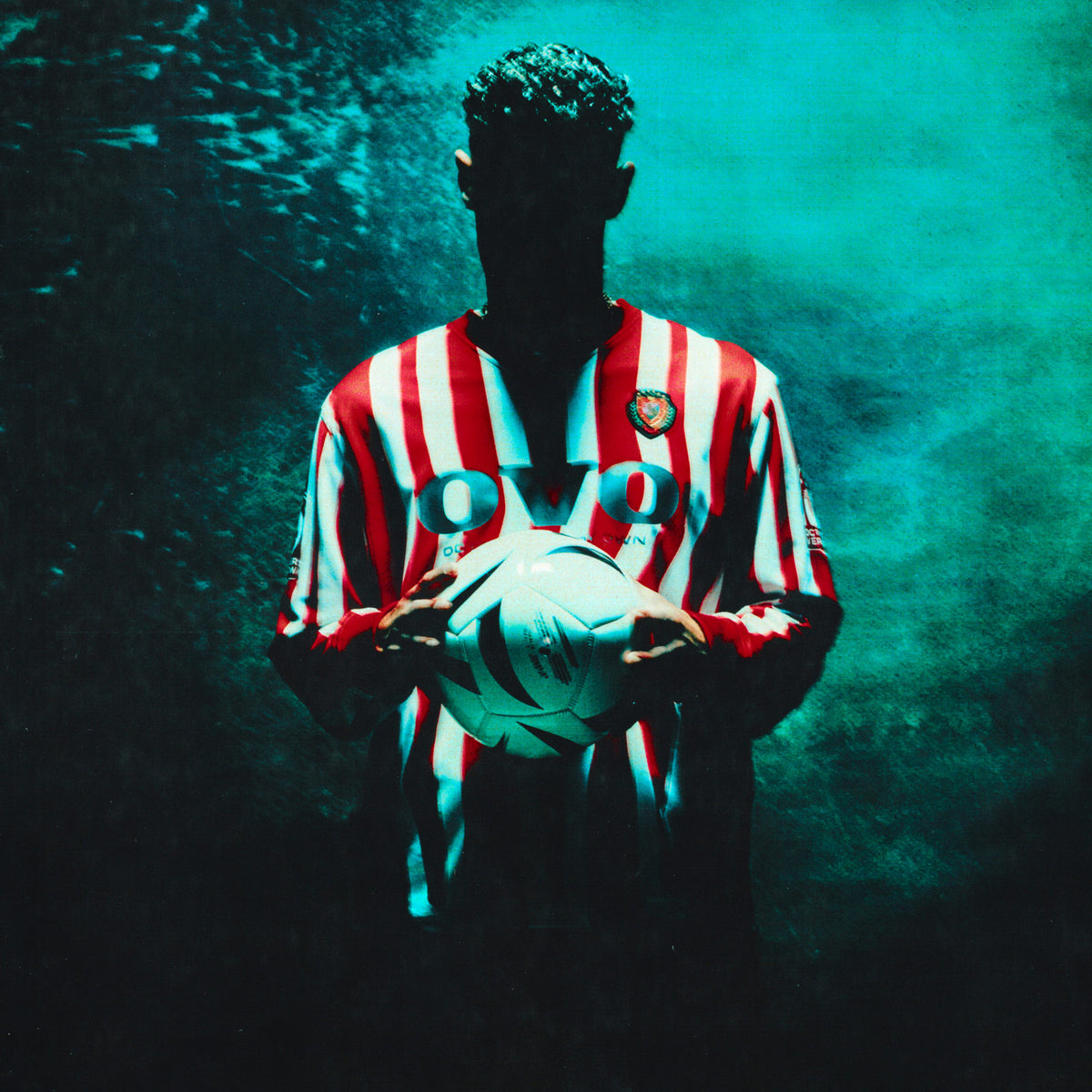 Person wearing a red and white October's Very Own striped jersey holding a soccer ball underwater.