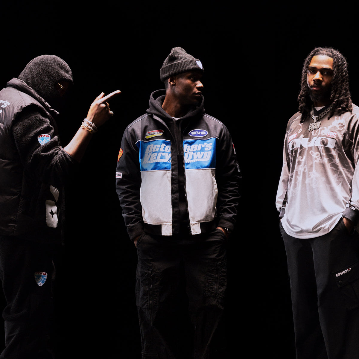 Three individuals wearing October's Very Own branded jackets and clothing against a black background