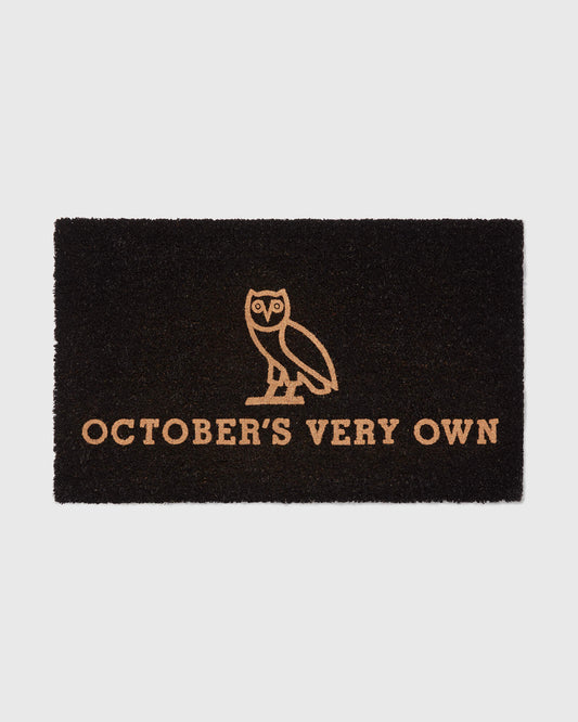 Black doormat with tan owl illustration and "October's Very Own" text.