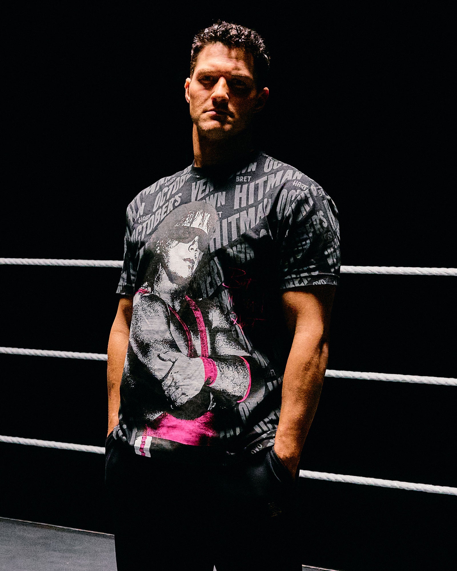 Man wearing a October's Very Own x WWE t-shirt with a design on a dark background