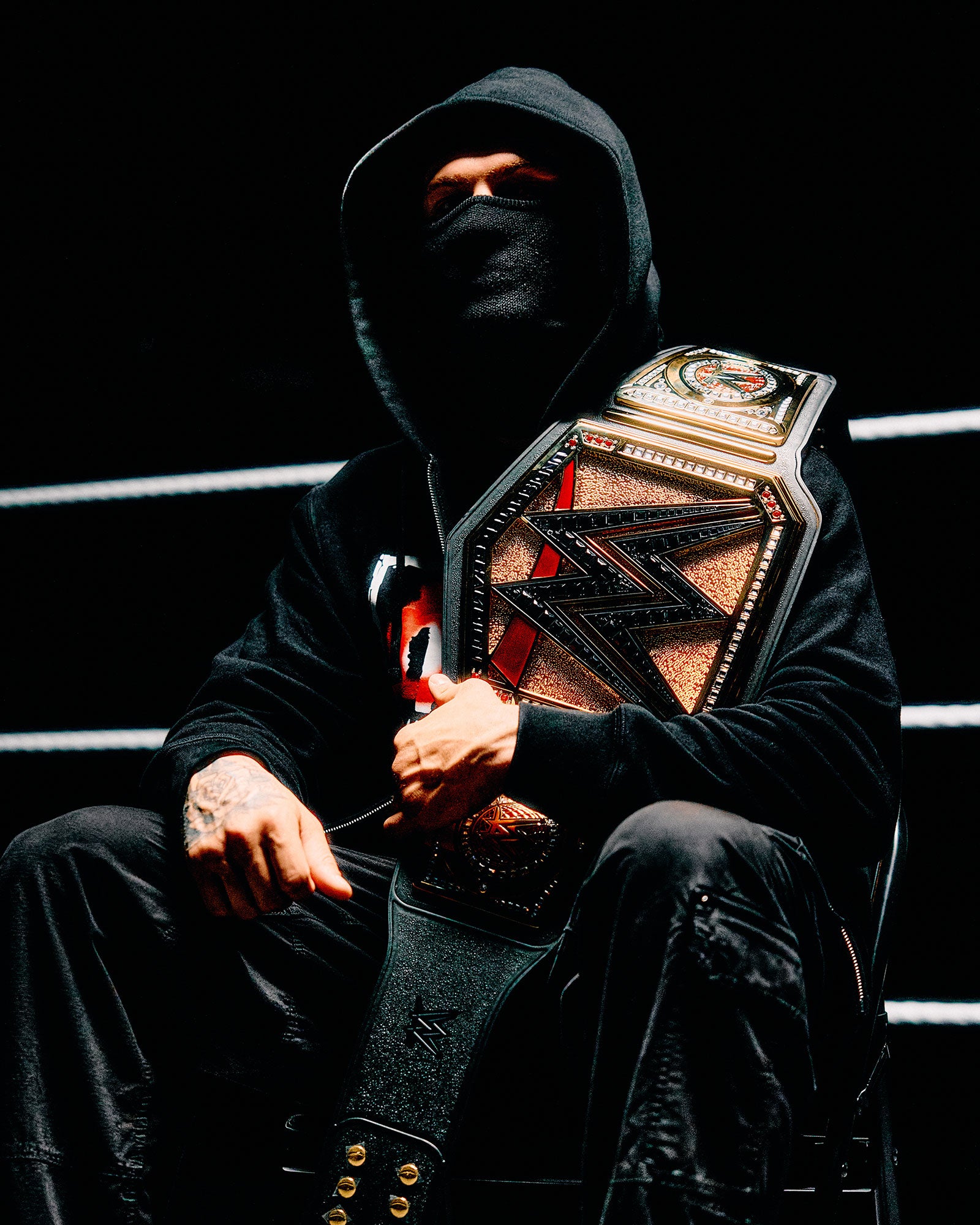 Person in October's Very Own x WWE clothing holding a championship belt in a wrestling ring.