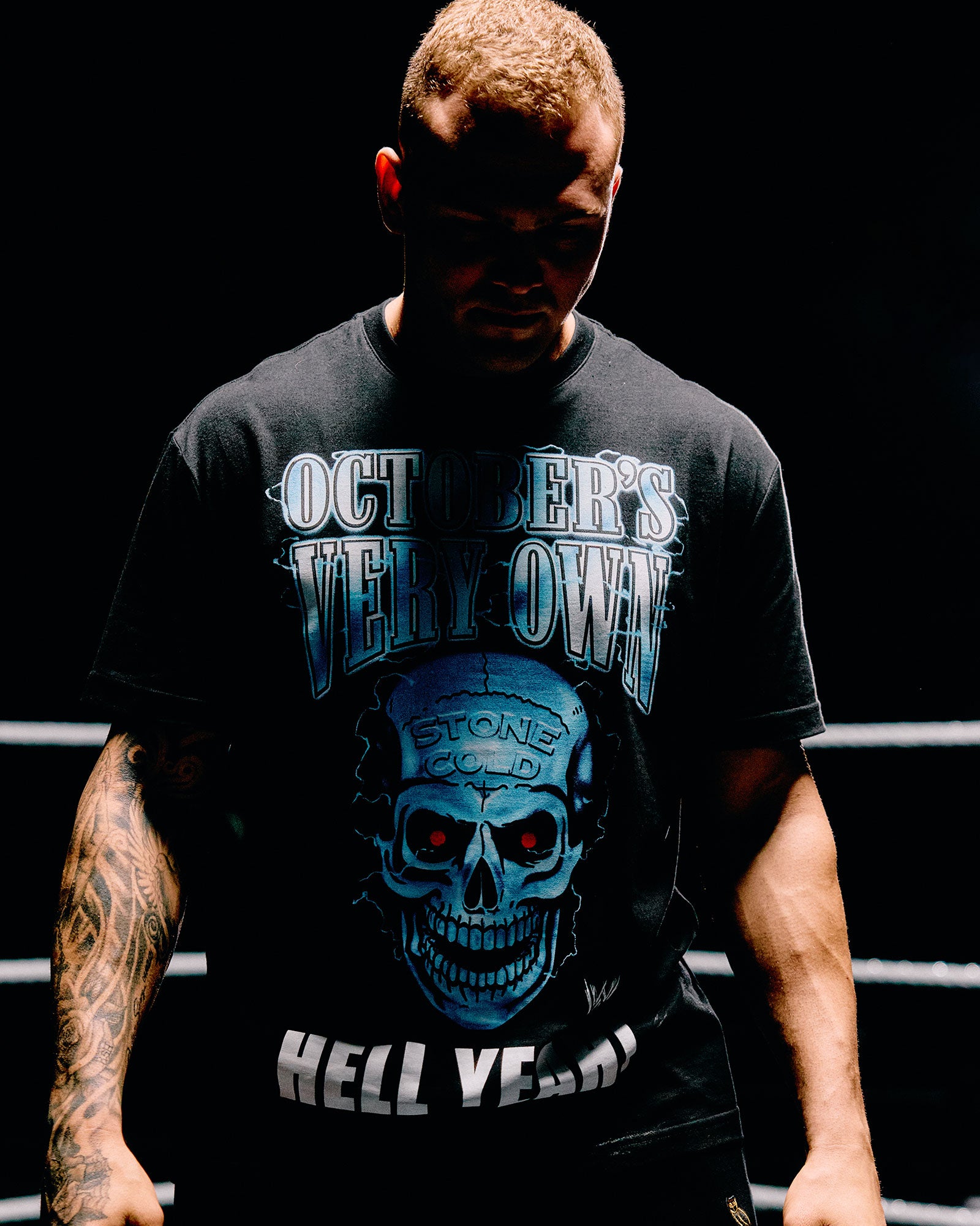 Person wearing a black October's Very Own x WWE t-shirt with a graphic design and text.