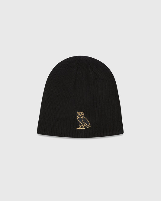 Black ribbed beanie with small gold owl embroidery on front.